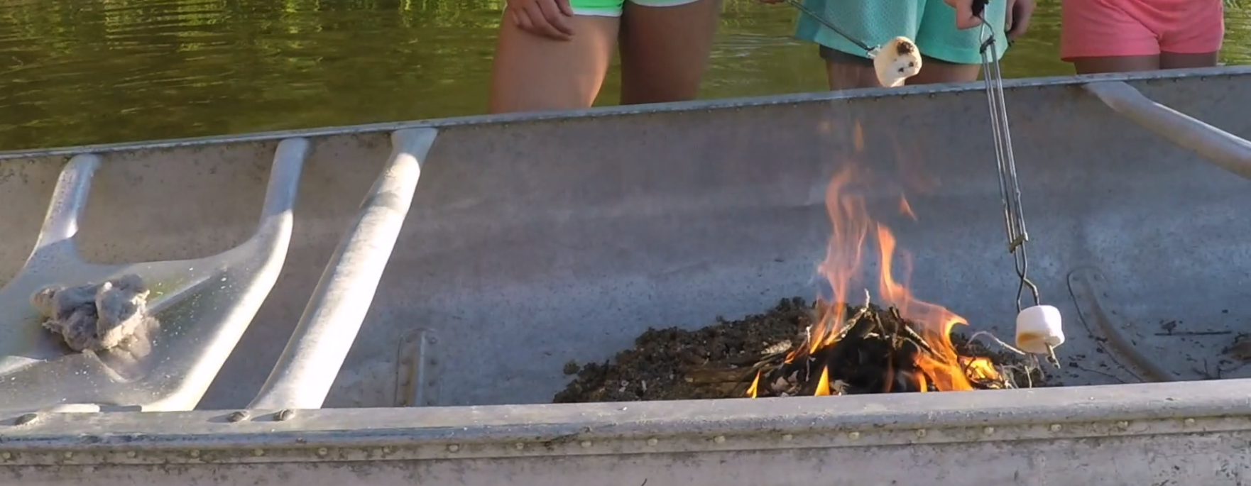 Girls Roasting Marshmallows over a Fire in a Canoe