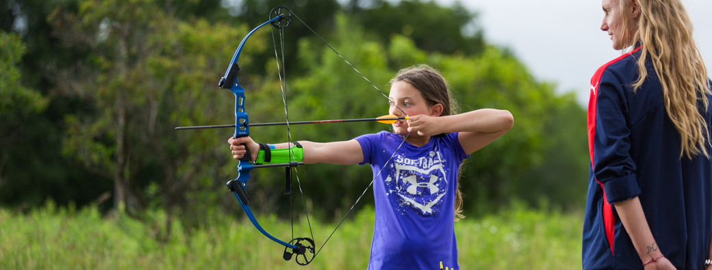 Girl Scout aiming at a target with her bow and arrow