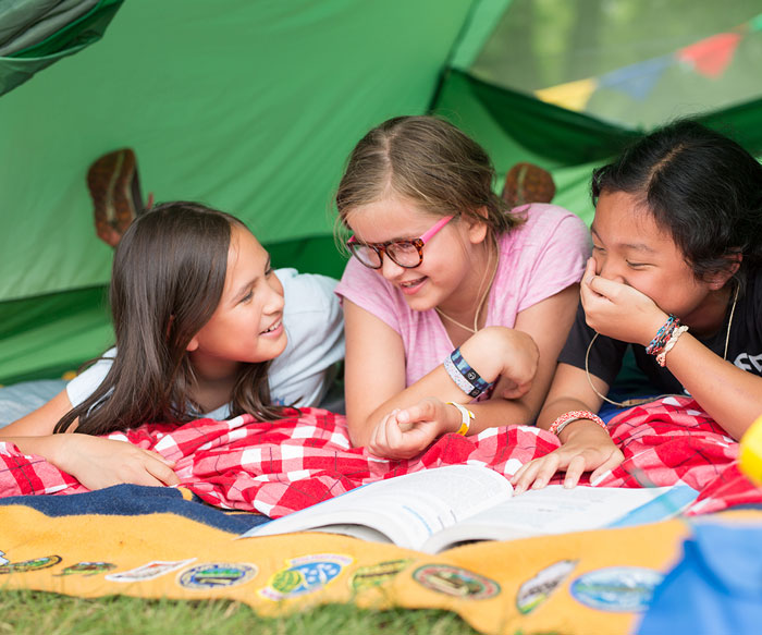 Three Girl Scouts in a green tent laughing